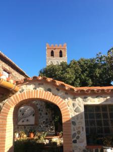 un bâtiment avec une arche et une tour d'horloge en arrière-plan dans l'établissement Mas Grandiflora, à Espira-de-lʼAgly