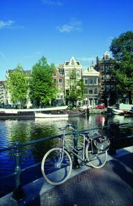 アムステルダムにあるNH コレクション バルビゾン パレス アパートメンツの水車の横に停められた自転車