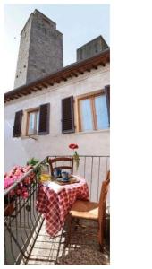 einen Balkon mit einem Tisch und Stühlen sowie ein Gebäude in der Unterkunft La Torre Useppi in San Gimignano