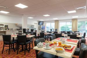 a cafeteria with tables and chairs with food on them at The Originals City, Hôtel Acadine, Pont-Audemer in Pont-Audemer