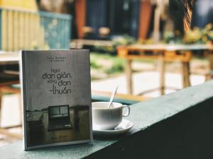 un libro sentado en una mesa junto a una taza de café en Fairyhouse Mộc Châu en Sơn La