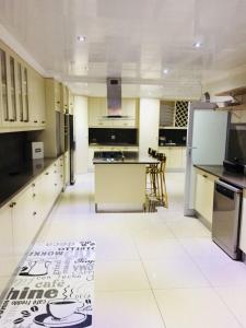 a kitchen with white cabinets and a white tile floor at 23 on Camden Guest House in East London