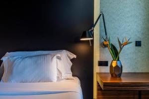 - une chambre avec un lit et un vase avec une plante sur une table dans l'établissement Evidencia Belverde Hotel, à Amora