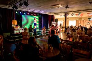 Eine Menge Leute sitzen in einem Restaurant und sehen einer Frau auf der Bühne zu. in der Unterkunft Camping Pods, Golden Sands Holiday Park in Dawlish
