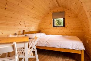 ein Schlafzimmer in einem Blockhaus mit einem Bett und einem Schreibtisch in der Unterkunft Camping Pods, Golden Sands Holiday Park in Dawlish + 9 Fotos