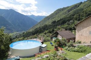 a hot tub in a yard with mountains in the background at Rustico in Verdabbio