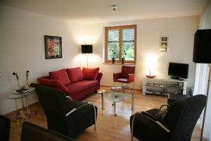 sala de estar con sofá rojo y sillas en Haus Kanisblick Appartements, en Schnepfau