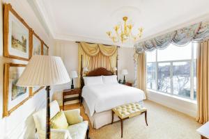a bedroom with a bed, chair, lamp and window at The Savoy in London