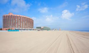 a large white building on a beach next to a large body of water at Grand Hotel Ocean City Oceanfront in Ocean City