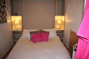 a bedroom with a bed with two pink pillows at The Hideaway at Duffryn Mawr Self Catering Cottages in Cowbridge
