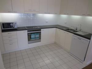 a white kitchen with a sink and a microwave at Lights Landing Apartments in Adelaide