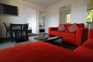 uma sala de estar com um sofá vermelho e uma mesa em Metropolitan Motel on Riccarton em Christchurch