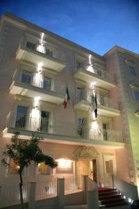 un grande edificio bianco con due balconi e una bandiera di Palace Hotel Vieste a Vieste