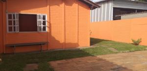 pomarańczowy dom z ławką przed nim w obiekcie Acomodaçaoes koynonya w mieście Sete Lagoas