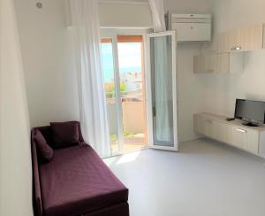 a living room with a purple couch and a window at Hotel & Residence Al Mare in Lido di Jesolo
