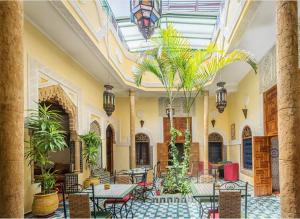 a lobby with tables and chairs and palm trees at Riad Dar Zouhour in Rabat