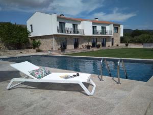 a white chair sitting next to a swimming pool at Carvalhal Redondo - Farm House in Castelo Novo