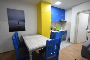 a small kitchen with a wooden table and blue chairs at Cozy and Lovely Appartment in Jagodina