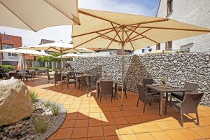 a patio with tables and chairs with umbrellas at Hotel Hirsch in Leonberg