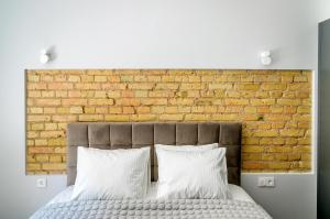 a bedroom with a brick wall and a bed with white pillows at Malunu Apartments 1 in Vilnius