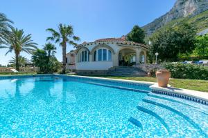 a villa with a swimming pool in front of a house at Villa Montgo Denia in Denia