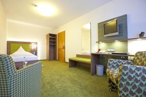 um quarto de hotel com uma cama e cadeiras e uma televisão em Hotel Hirsch em Leonberg