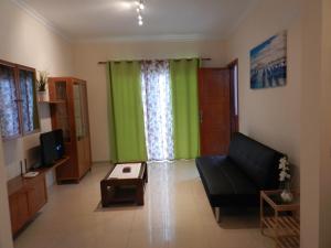 a living room with a black couch and green curtains at Trotamundos GC FAMILIAS Y ADULTOS RESPONSABLES in El Tablero