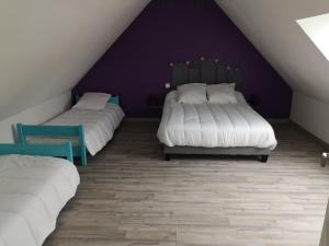 Zimmer im Dachgeschoss mit 2 Betten und einer lila Wand in der Unterkunft Gîte à la ferme du Bailly - Baie de Somme in Saint-Quentin-Lamotte-Croix-au-Bailly