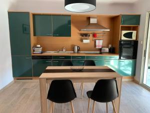 a kitchen with green cabinets and a wooden table at BEAU T4 100M2 PALAIS DES ROIS DE MAJORQUE in Perpignan