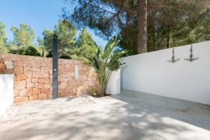 a white fence with a stone wall and a tree at Nyumba ya Sun in Cala Tarida