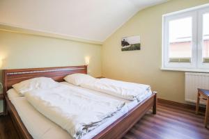 a bedroom with a bed with white sheets and a window at Buedlfarm-Nord in Sahrensdorf