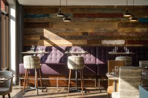 un restaurante con asientos morados y una pared de madera en Novotel Ipswich Centre en Ipswich