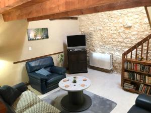 ein Wohnzimmer mit einer Couch, einem Tisch und einem Fernseher in der Unterkunft LES GRANGES in Les Lèves-et-Thoumeyragues