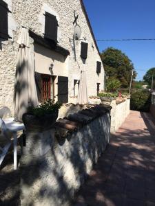 eine Steinmauer mit einem Regenschirm und einem Gebäude in der Unterkunft LES GRANGES in Les Lèves-et-Thoumeyragues