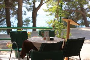 a table with green chairs and a table with a table cloth at Pansion "Roko" in Drvenik