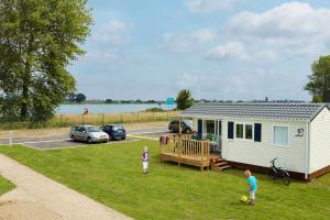 dos niños jugando en la hierba delante de una casita en Kustpark Nieuwpoort en Nieuwpoort