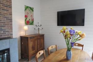 eine Vase mit Blumen auf einem Tisch und einem TV in der Unterkunft LA GRANGE in Montlouis-sur-Loire