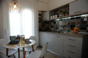 eine Küche mit einem Tisch, Stühlen und einem Waschbecken in der Unterkunft Stamatia Apartments in Asprovalta