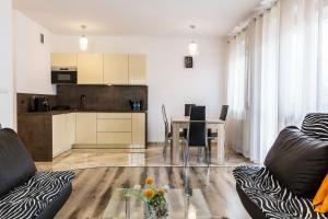 a living room with a table and a kitchen at TatryTop Apartamenty Zaciszne in Zakopane