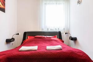 a bedroom with a red bed with two pillows at TatryTop Apartamenty Zaciszne in Zakopane