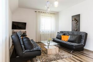 a living room with two black leather chairs and a table at TatryTop Apartamenty Zaciszne in Zakopane