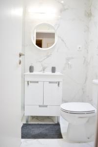 a white bathroom with a toilet and a mirror at Belém River Apartment in Lisbon