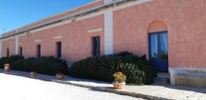un bâtiment rouge avec des plantes en pot devant lui dans l'établissement Relais Casa Mirabile, à Menfi