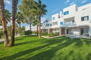 Cala Llenya Resort Ibiza في كالا يينيا: اطلالة خارجية على مبنى ابيض كبير عليه نخيل
