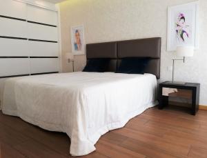 1 dormitorio con 1 cama blanca grande y mesa auxiliar en Apartamentos Turisticos da Nazare en Nazaré