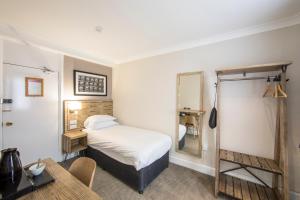 a bedroom with a bed and a table and a mirror at Half Moon, Sherborne by Marston's Inns in Sherborne