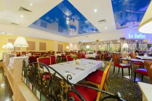 un restaurante con una mesa blanca y sillas rojas en Hotel Korston Royal Kazan, en Kazán