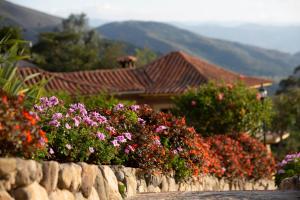 a stone wall with flowers in front of a house at Casas La Primavera in Villa de Leyva