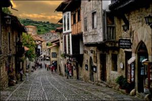 a cobblestone street in an old town with people walking down it at Posada Ansorena in Santillana del Mar