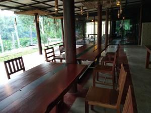 una fila de mesas y sillas de madera en un restaurante en Boutique Raft Resort, River Kwai, en Sai Yok